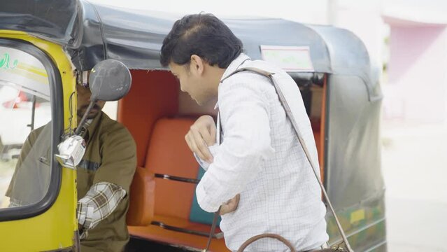 Passenger paying money to auto rickshaw driver after ride - concept of earnings, transportation and commutation