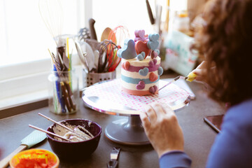 Unrecognizable person giving the last touches to a cake. Selective focus. Creative pastry.