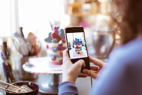 Unrecognizable person taking a picture of a cake with his mobile phone. Selective focus. Space for text.