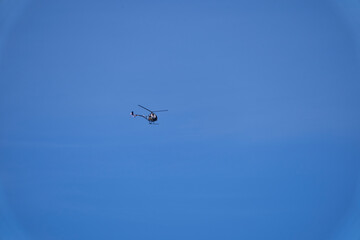 Fototapeta na wymiar Small Helicopter flying against the blue sky