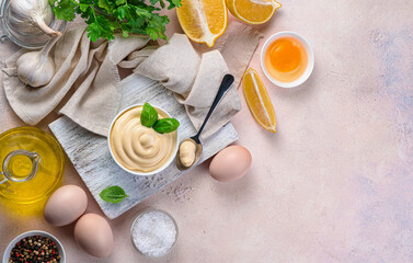 Homemade mayonnaise and ingredients with spices on a light pink background. Top view, copy space.