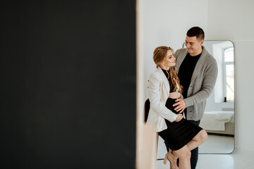 Beautiful pregnant woman and her handsome husband are hugging and smiling while spending time...