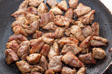 Pork meat is fried in a pan. Drops of oil in a frying pan.