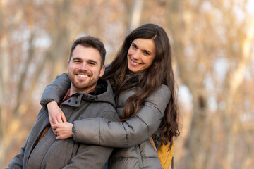 Young couple in love hugging in the park and looking at camera