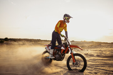 Motocross rider on sportmotor over dust landscape