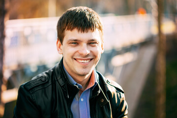 Close Up Portrait Young Caucasian Handsome Man In Black Leather Jacket Outdoor In Spring Sunny Day.