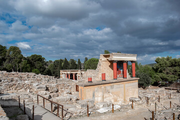 Minoan palace Knossos at Heraklion, Crete island, Greece. North Entrance with charging bull fresco and three red columns against a dramatic cloudy sky