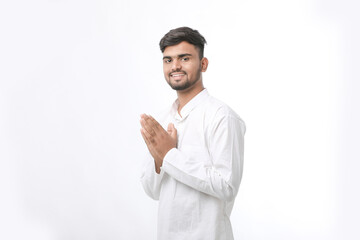 Young indian man in traditional wear and giving namaste or welcome gesture.
