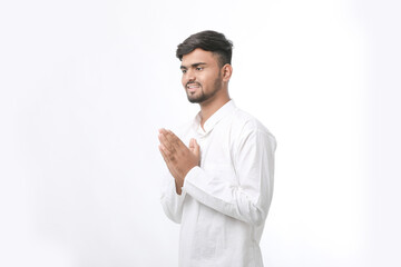 Young indian man in traditional wear and giving namaste or welcome gesture.
