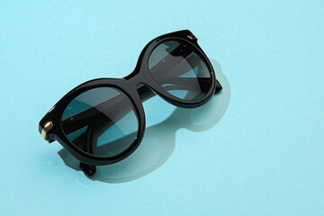 Women summer sunglasses on pastel blue background in sunlight. Modern stylish sunglasses for...