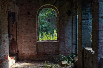 A window in a brick house ruins by summer day. Window view of an abandoned manor house