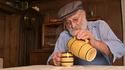 Alter Mann Bauer trinkt Most aus einem Krug.