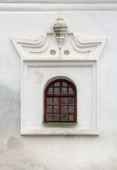 Arched latticed window in a white church wall with stucco decoration