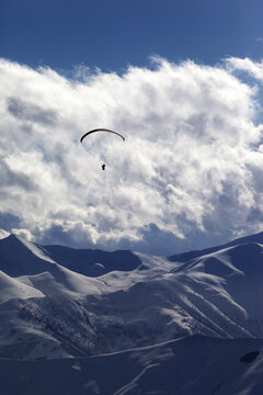 Winter mountain with clouds and silhouette of parachutist