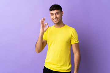 Young Colombian man isolated on purple background showing ok sign with fingers