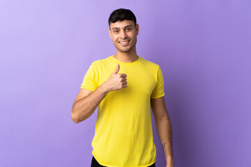 Young Colombian man isolated on purple background giving a thumbs up gesture