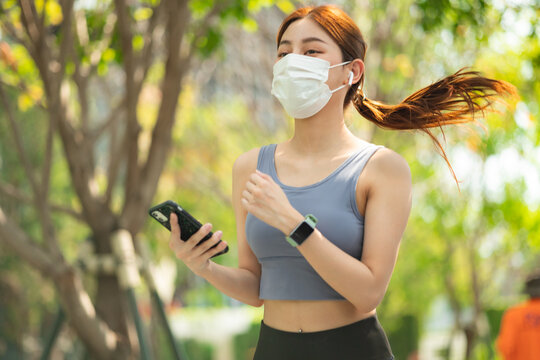 Asian runner jogging in the park during covid-19 pandemic. Working out in the days of the coronavirus.Fit woman jogging at outdoor .Healthy lifestyle concept. she have pois protective mask on face.