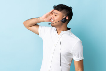 Telemarketer Colombian man working with a headset over isolated background smiling a lot