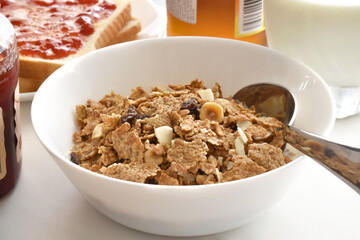 Fruit and fiber cereal and toast with strawberry jam, glass jar of strawberry jam, glass jar of orange jam and glass of milk on the table. Healthy breakfast concept. 