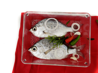 Gerres Fish (Gerres Filamentosus) Whipfin silver biddy Fish, Decorated with vegetables on a glass bowl, White Background.Selective Focus