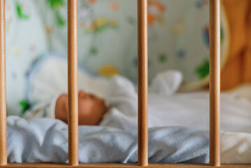 Baby newborn sleeps in the bed. safe fencing children protection
