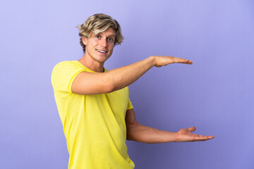 English man over isolated purple background holding copyspace to insert an ad