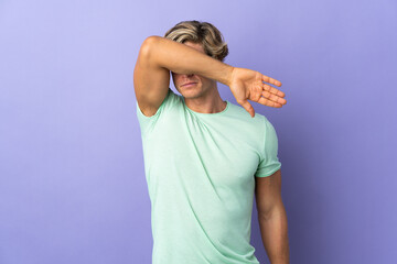 English man over isolated purple background covering eyes by hands
