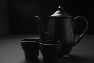 Teiera e tazzine nere controluce