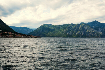 Bad weather in the Bay of Kotor in Montenegro. Clouds, sea, mountains, village. Scenic coastline view