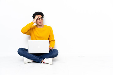 Venezuelan man sitting on the floor with laptop smiling a lot