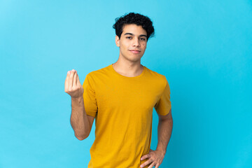 Young Venezuelan man isolated on blue background making Italian gesture