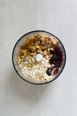 The process of making energy bars at home. Oatmeal, cranberries, raisins, pumpkin seeds, nuts. Dry ingredients are placed in a blender for blending. Healthy food concept. Top view.