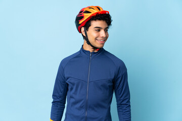 Venezuelan cyclist man isolated on blue background looking to the side and smiling - obrazy, fototapety, plakaty