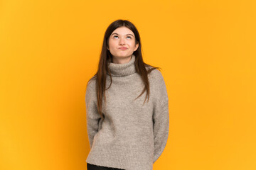 Fototapeta premium Young Ukrainian girl isolated on yellow background and looking up