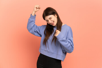 Young Ukrainian girl isolated on pink background celebrating a victory