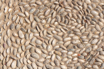 Beautiful texture of path of gray and white smooth stones on the yellow background with sand is in the park