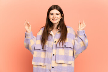 Young Ukrainian girl isolated on pink background in zen pose