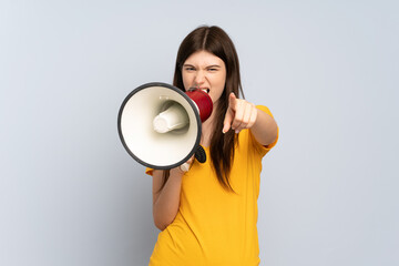 Young Ukrainian girl isolated on white background shouting through a megaphone to announce something while pointing to the front