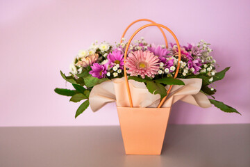 A composition of flowers in a festive box stands on the stairs with lighting. A gift for a beloved woman