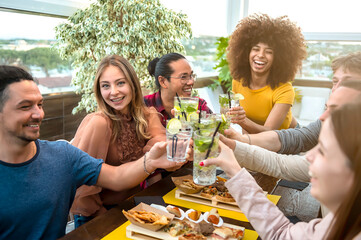 Best friends toasting mojito drinks at fashion cocktail restaurant at happy hour time - Young people having party time at rooftop pub - Concept with young people having drunk fun toasting drinks.