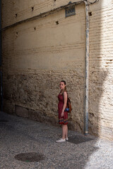 Fototapeta na wymiar Traveler young girl in red dress in old alley