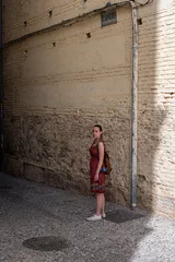 Fotobehang Traveler young girl in red dress in old alley © Adolf