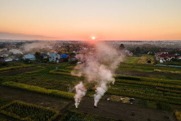 Aerial view of agricultural waste bonfires from dry grass and straw stubble burning with thick smoke polluting air during dry season on farmlands
