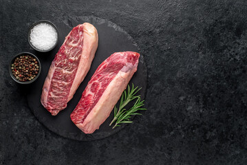 Two raw picanya steaks with spices on stone background with copy space for text