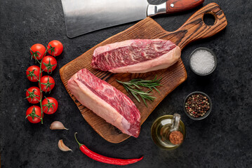 Two raw picanha steaks with spices on a stone background