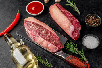 Two raw picanha steaks with spices on a stone background