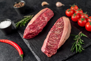 Two raw picanha steaks with spices on a stone background