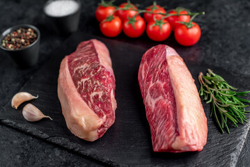 Two raw picanha steaks with spices on a stone background