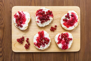 Healthy breakfast, toasts with curd cheese, berry jam and red currant berries, diet food, on a wooden background, selective focus, top view.