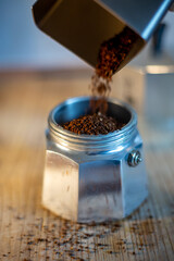 Pouring freshly ground coffee into a moka pot